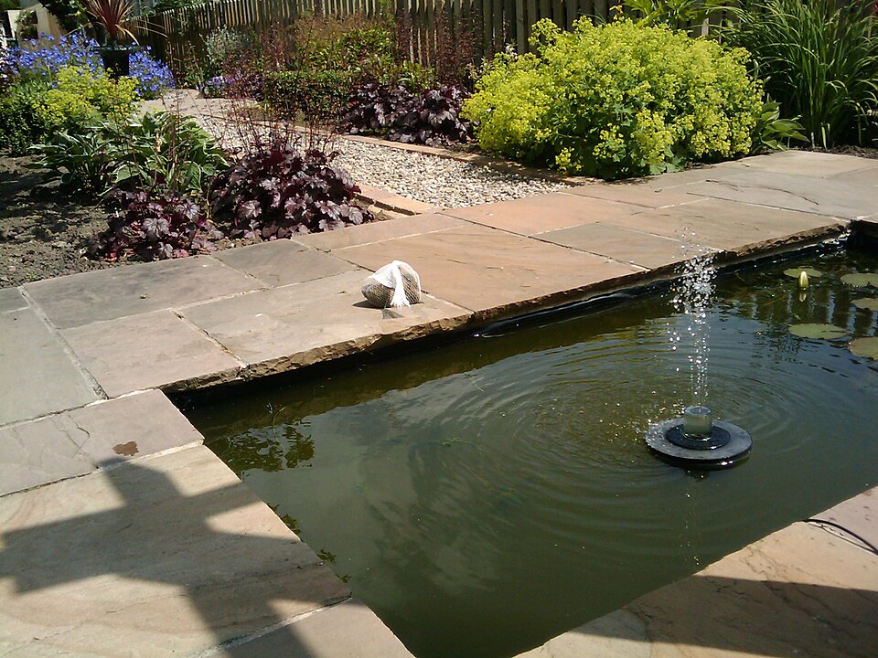 Une fontaine solaire flottante en plein travail dans un bassin de jardin : le jet vit et meurt au rythme du soleil.