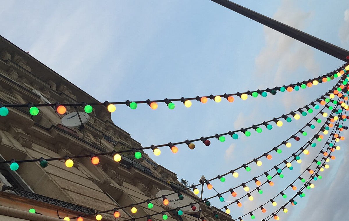 Guirlandes guinguette tendues au-dessus d'une rue parisienne un soir d'été